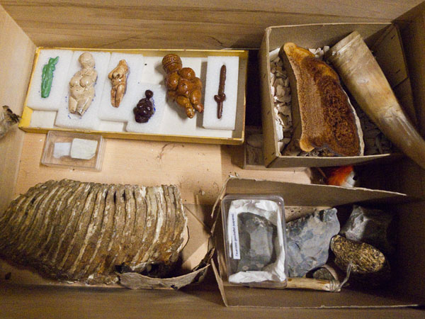Eine hölzerne Kiste, die unterschiedliche Tastmaterialien zum Thema Steinzeit beinhaltet; unter anderem ein Abguss der Venus von Willendorf.