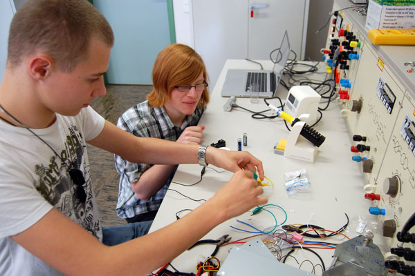 Schüler des SZU löten und testen eine batteriebetriebene Infrarot LED, die sich über einen Taster einschalten lässt.